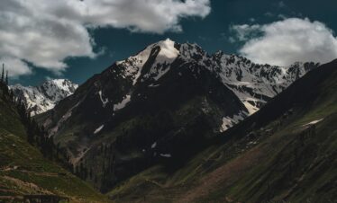 Breathtaking view of the snow-capped mountains in Murree, Pakistan under a bright cloudy sky.