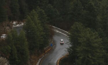 A high-angle view of a winding road through a lush forest in Changla Gali, Pakistan.