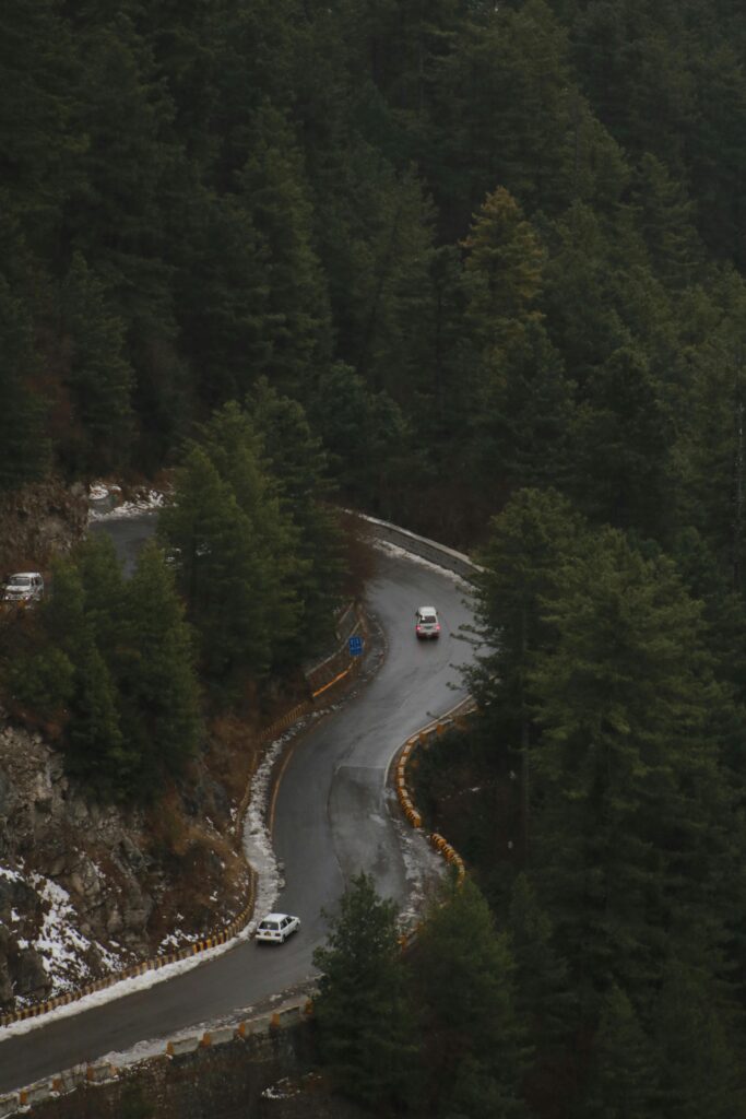 A high-angle view of a winding road through a lush forest in Changla Gali, Pakistan.
