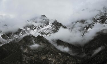 Capture of rugged snow-capped mountains shrouded in mist, creating a mysterious and tranquil landscape.