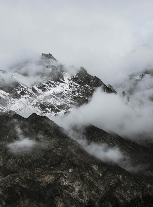 Capture of rugged snow-capped mountains shrouded in mist, creating a mysterious and tranquil landscape.